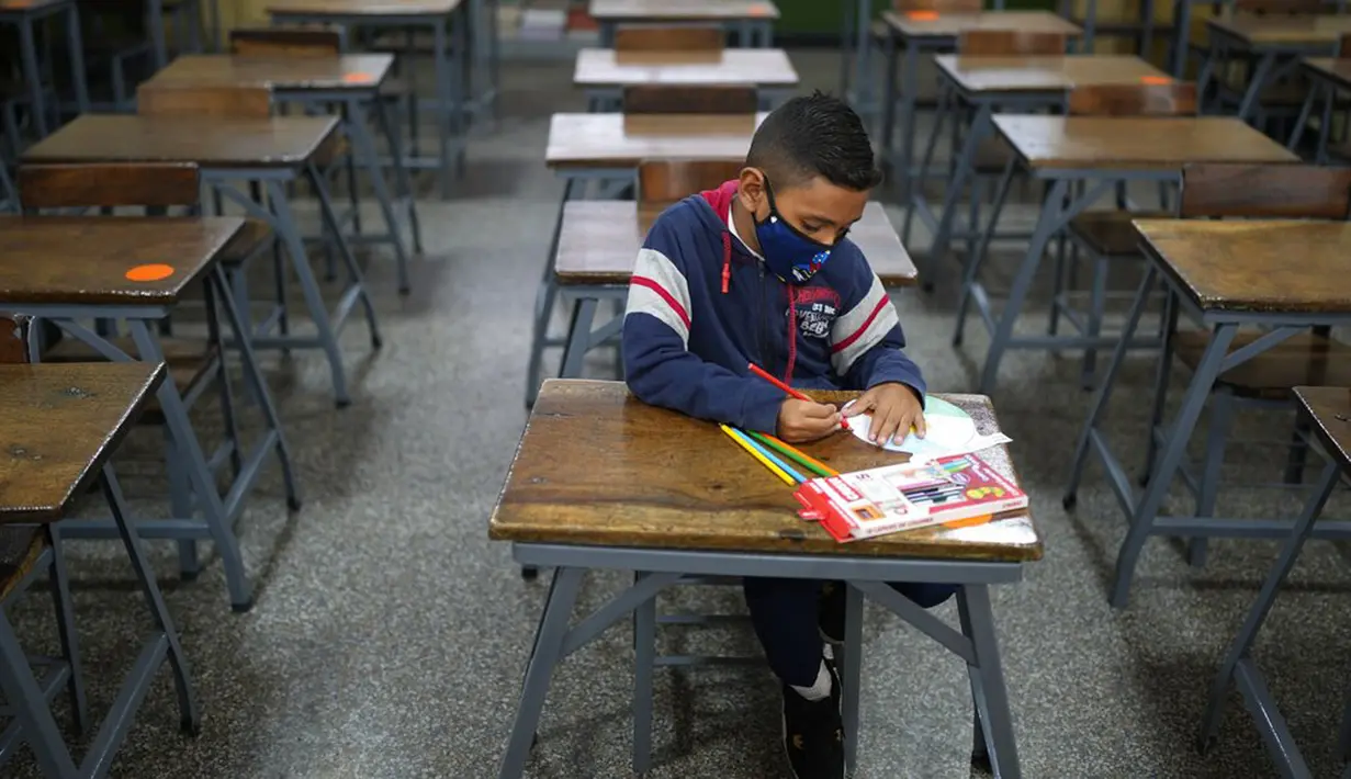 Sebastian (7) mengikuti kelas matematika sendirian pada hari pertama kembali ke sekolah tatap muka sejak dimulainya pembatasan pandemi COVID-19 di Sekolah Andres Bello, Caracas, Venezuela, 25 Oktober 2021. (AP Photo/Ariana Cubillos)