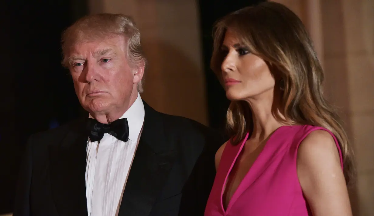 Melania Trump mendampingi Donald Trump saat menghadiri gala tahunan Palang Merah Amerika ke-60 di Mar-a-Lago, Florida, AS (4/2). First Lady Melania Trump tampil anggun dengan mengenakan gaun berwarna merah muda. (AFP/Mandel Ngan)