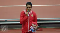Atlet lompat jauh Indonesia, Maria Londa berhasil meraih emas di nomor lompat jauh putri SEA Games 2015 di National Stadium, Singapura, Rabu (10/6/2015). Maria mencium medali usai pengalungan. (Liputan6.com/Helmi Fithriansyah)