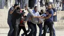 Sejumlah warga Palestina membawa seorang pria yang terluka saat bentrok dengan polisi Israel kompleks masjid al-Aqsa di Yerusalem (11/8/2019). Perayaan Idul Adha hari ini juga bertepatan dengan hari libur umat Yahudi yang dikenal dengan Tisha B'av. (AP Photo/Mahmoud Illean)