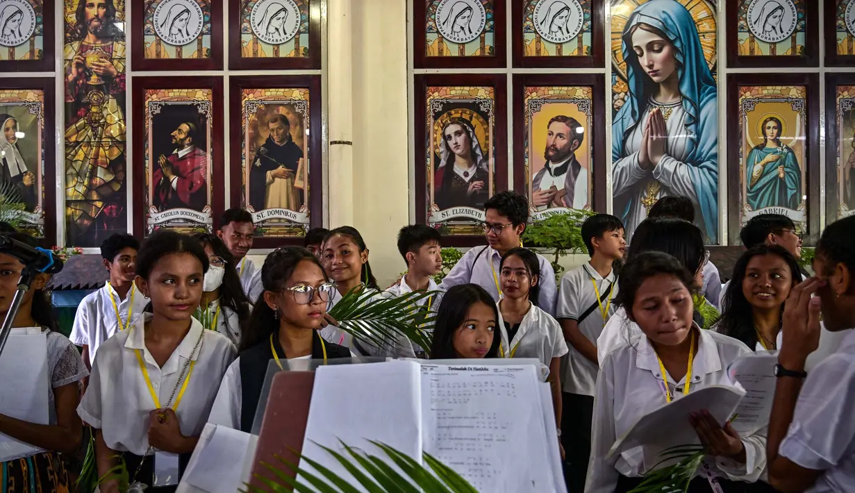 Paduan suara gereja Katolik mempersiapkan daun palem selama prosesi untuk menandai Minggu Palem di Gereja Kelahiran Bunda Maria, yang juga dikenal sebagai Gereja Katolik Kelahiran Santa Perawan Maria, di Surabaya pada 13 April 2025. (JUNI KRISWANTO/AFP)
