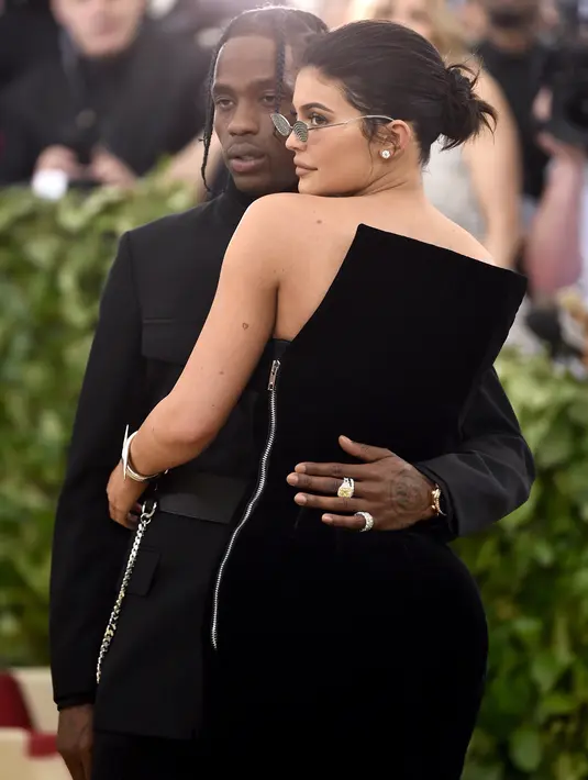 Kylie Jenner memeluk sang kekasih, Traviz Scott saat berpose untuk fotografer setibanya pada ajang Met Gala 2018 di Metropolitan Museum of Art New York, Senin (7/5). Kylie Jenner dan Travis Scott serasi tampil serba hitam. (Evan Agostini/Invision/AP)
