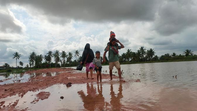 Satu keluarga asal Desa Sungai Jawi Palembang tampak senang saat melewati jalan yang dibangun anggota Kodim 0418/Palembang dalam rangka TMMD ke-110. Jalan yang dulu berlumpur dan sulit dilewati, kini lebih mudah dilintasi ( / Nefri Inge)