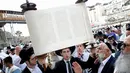 Seorang umat Yahudi memegang gulungan Taurat saat mengikuti doa massal selama liburan Sukkot di depan Tembok Ratapan di Kota Tua Yerusalem, (19/10). (REUTERS/Baz Ratner)