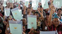 Warga menunjukkan sertifikat tanah saat mengikuti penyerahan sertifikat hak atas lahan tanah oleh Presiden Joko Widodo (Jokowi) di halaman depan Stadion Pakansari, Cibinong, Bogor, Selasa (25/9). (Merdeka.com/Arie Basuki)