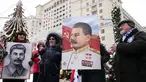 Orang-orang berfoto sambil memegang potret pemimpin Soviet Josef Stalin sebelum meletakkan bunga di makamnya menandai peringatan 142 tahun kelahirannya di dekat Tembok Kremlin di Lapangan Merah di Moskow, Rusia, Selasa (21/12/2021). (AP Photo/Alexander Zemlianichenko)