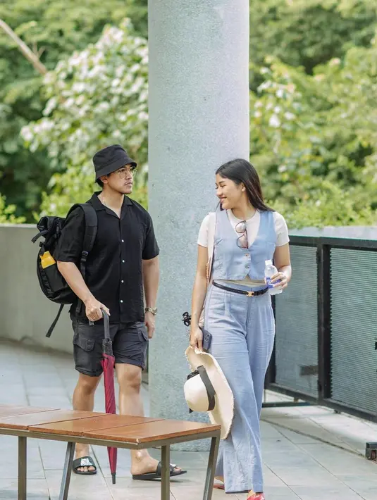 Kaesang tampil dengan all-black outift bersama Erina yang memilih outfit berwarna baby blues yang lembut. Kaesang mengenakan kemeja lengan pendek, dipadu celana kargo pendek, sandal, dan topi hitam. Sedangkan Erina tampil memikat dengan kaus putih lengan pendek, dilapisi dengan cropped vest biru muda yang serasi dengan celana panjangnya. Foto: Instagram.
