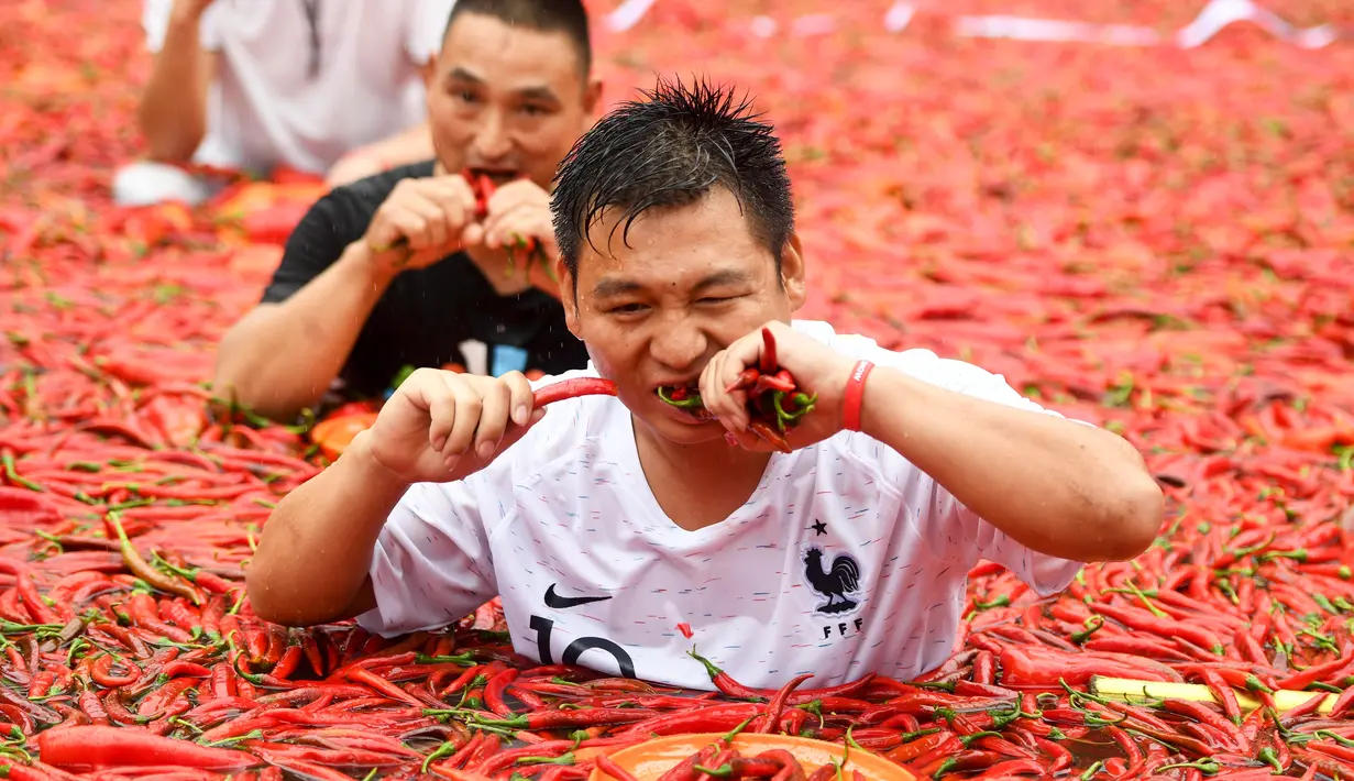 Kontestan memakan cabai saat mengambil bagian dalam kompetisi makan cabai di Ningxiang di provinsi Hunan tengah, China (8/7). Pemenang dalam kontes ini telah memakan 5 cabai dalam waktu satu menit. (AFP Photo)