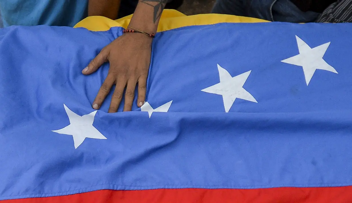 Bendera negara Venezuela yang bawa saat mengiringi pemakaman Jose Francisco Guerrero di San Cristobal, Tachira State, Venezuela (19/5). Jose tewas akibat tembakan saat ia terjebak dalam konfrontasi antara demonstran dan polisi setempat. (AFP/Luis Robayo)