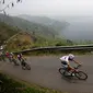 Para pebalap sepeda melewati tanjakan di samping Danau Singkarak dalam Etape 4 Tour de Singkarak 2015 antara Sawahlunto-Solok Selatan, Selasa (6/10/2015). (Bola.com/Arief Bagus)