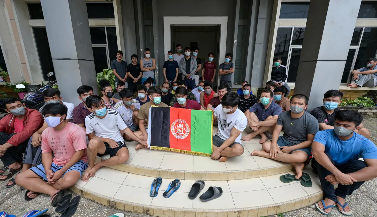 Pengungsi Afghanistan mengibarkan bendera negaranya untuk menunjukkan identitasnya di sebuah kamp pengungsi di Bekasi, Jawa Barat (20/8/2021). Mereka tidak bersedia kembali ke negaranya, terutama setelah Taliban mengambil alih kekuasaan dari pemerintahan Presiden Ashraf Ghani. (AFP/Bay Ismoyo)