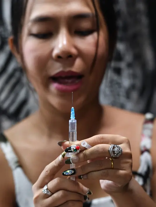 Jessica Nguyen saat akan melakukan suntik hormon di tokonya, Ho Chi Minh, Vietnam (30/3). Pemerintah Vietnam belakangan telah merancang UU mengenai hukum yang akan memungkinkan orang untuk secara resmi mengubah jenis kelamin. (AFP Photo/Hoang Dinh Nam)