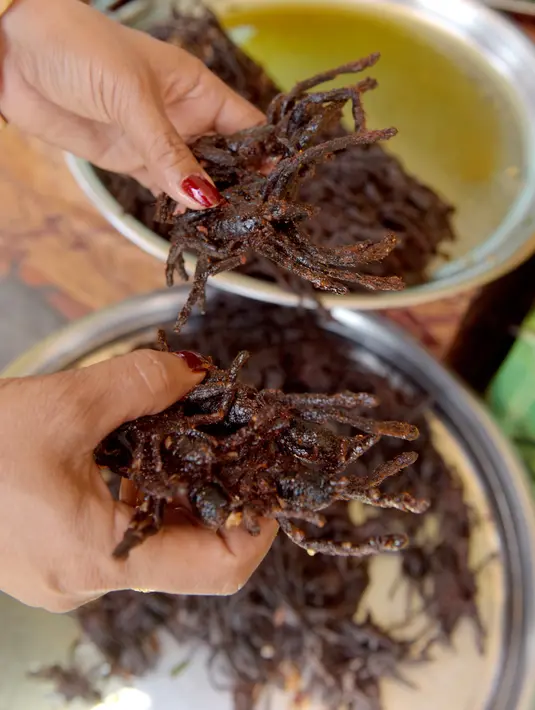 Penjual menyajikan kuliner tarantula goreng di wilayah Skun, Provinsi Kampong Cham, Kamboja, 14 Maret 2018. Tarantula paling enak dibumbui garam dan bawang putih, kemudian digoreng dalam minyak panas. (TANG CHHIN Sothy / AFP)