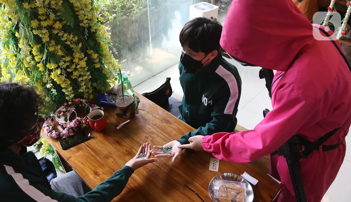 Pengunjung bermain salah satu permainan dalam serial Netflix Squid Game di Cafe Strawberry, Jakarta, Sabtu (16/10/2021). Cafe tersebut berinovasi dengan mengusung tema permainan dalam film asal Korea Selatan, Squid Game untuk memberikan daya tarik bagi pengunjung. (Liputan6.com/Herman Zakharia)