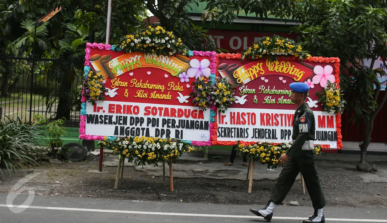 Seorang petugas melintas di depan jajaran karangan bunga ucapan selamat dari politisi PDIP, di sekitar tempat resepsi Gibran Rakabuming Raka-Selvi Ananda, di Gedung Graha Saba Buana, Solo, Rabu (10/6/2015). (Liputan6.com/Faizal Fanani)