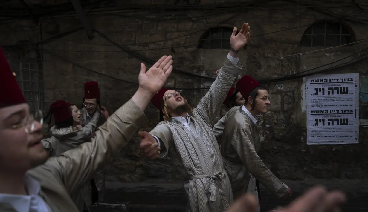 Yahudi ultra-Ortodoks mengenakan kostum dan menari selama festival Yahudi Purim di Yerusalem, Jumat (18/3/2022). Hari libur Yahudi Purim memperingati keselamatan orang-orang Yahudi dari genosida di Persia kuno, seperti yang diceritakan dalam Kitab Ester. (AP Photo/Oded Balilty)
