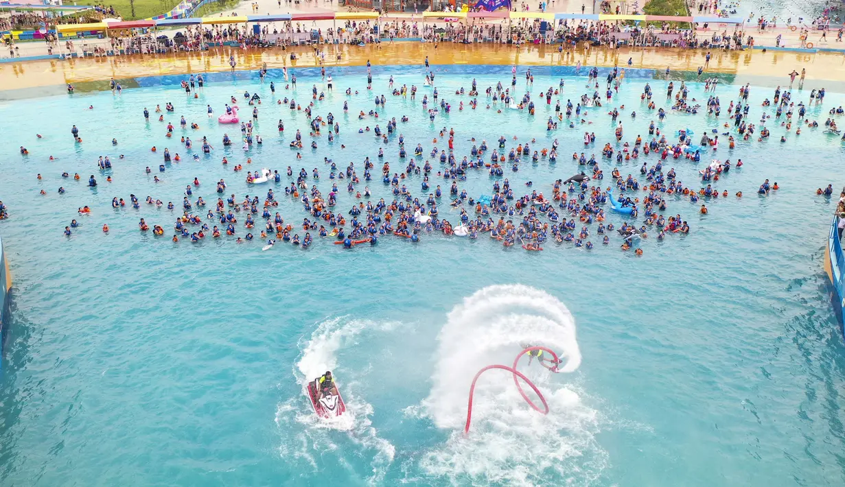 Suasana foto udara warga China bersantai di kolam renang Lianyungang, provinsi Jiangsu timur, China (4/7/2021). Di tengah pandemi Covid-19, warga China asyik menonton pertunjukan papan luncur saat mereka mendinginkan diri di kolam renang sambil bersantai. (AFP/STR)