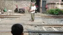 Penjaga perlintasan kereta api tanpa palang pintu, Wandi, berdiri tepat di samping perlintasan di Kawasan Petamburan, Jakarta, Jumat (4/6/2021). Di usianya yang tidak lagi muda, Pak Wandi tetap ada di mata pengendara dan pejalan kaki yang melintas di antara pemukiman warga. (merdeka.com/Imam Buhori)