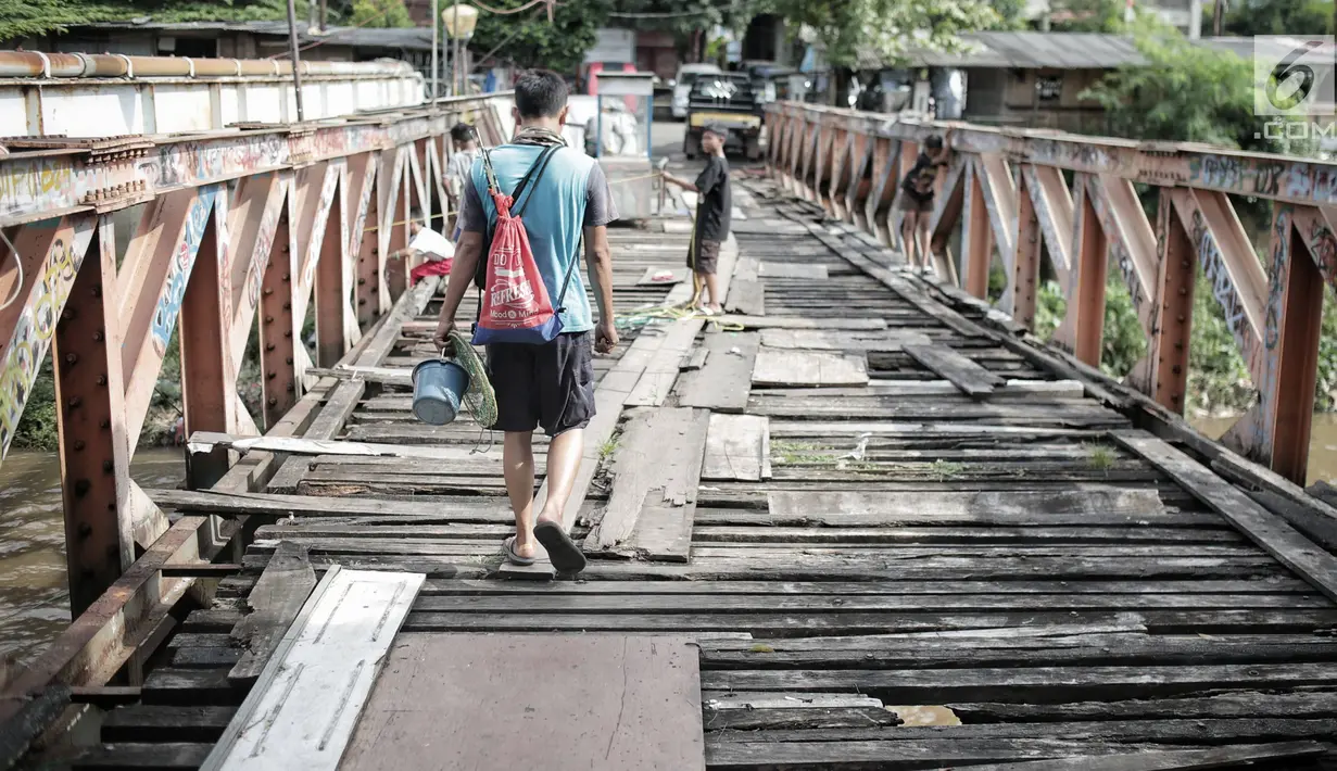 Warga melintasi jembatan dari kayu yang menjadi penghubung antara Jalan Karet Pasar Baru VII, Karet Tengsin dan Jalan Pam Baru, Bendungan Hilir, Tanah Abang, Rabu (30/1). (Liputan6.com/Faizal Fanani)