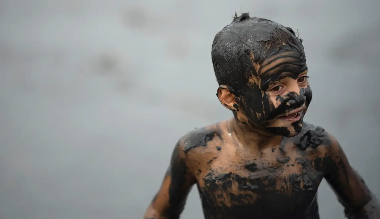 Seorang anak tersenyum saat mengikuti "Bloco da Lama", pesta mandi lumpur di Paraty, negara bagian Rio de Janeiro, Brasil (2/3). Bermain lumpur di tempat ini merupakan acara tradisional di kota bersejarah, Paraty. (AFP Photo/Mauro Pimentel)