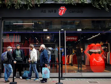 Orang-orang mengantre untuk memasuki toko andalan The Rolling Stones yang baru sebelum hari pertama pembukaannya di London, Rabu (9/9/2020). Rolling Stones membuka membuka toko pertamanya di 9 Carnaby Street. (Tolga Akmen / AFP)