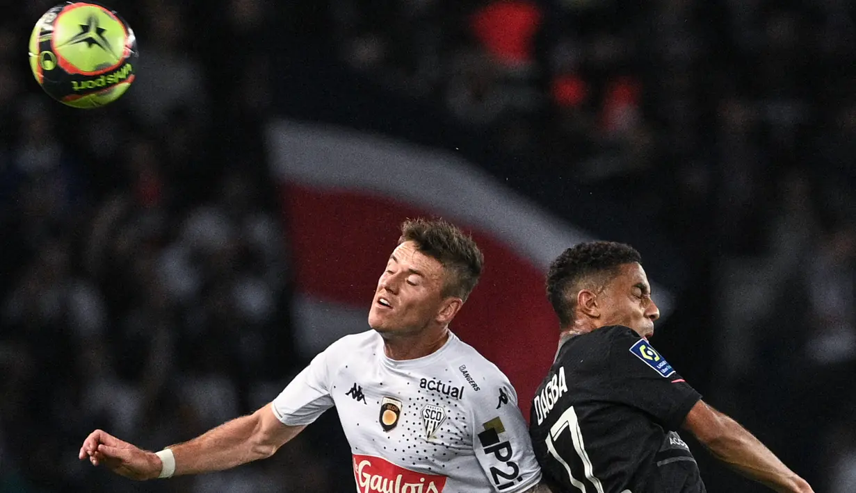 Gelandang Angers Pierrick Capelle (tengah) dan bek Paris Saint-Germain (PSG) Colin Dagba berebut bola pada pekan ke-10 Ligue 1 Prancis 2021/2022 di Parc des Princes, Sabtu (16/10/2021) dini hari WIB. PSG memastikan kemenangan 2-1 lewat gol penalti Kylian Mbappe. (FRANCK FIFE / AFP)