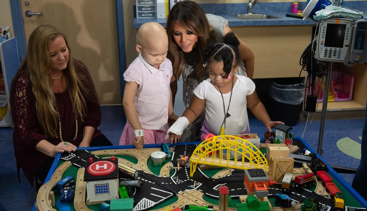 Ibu Negara AS, Melania Trump bermain dengan pasien anak, Essence dan Natalayah saat mengunjungi Rumah Sakit Anak Monroe Carell Jr. di Nashville, Selasa (24/7). Kedatangan Melania untuk berdiskusi terkait Neonatal Abstinence Syndrome (NAS). (AFP/SAUL LOEB)