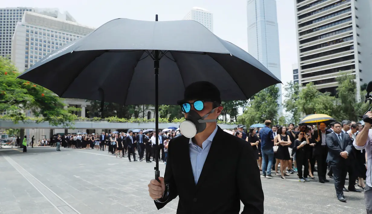 Seorang pengacara membawa payung dan mengenakan topeng saat berdemonstrasi di Hong Kong, Rabu (7/8/2019). Para pengacara Hong Kong telah dua kali terlibat dalam aksi protes terhadap RUU Ekstradisi. (AP Photo/Kin Cheung)