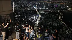 Pengunjung memakai masker untuk melindungi dari penyebaran Covid-19, berselfie saat menginap di lokasi perkemahan semalam di atap gedung pencakar langit di Seoul, Korea Selatan (7/8/2020). Menara Lotte World, setinggi 555 meter gedung pencakar langit dengan 123 lantai. (AP Photo/Lee Jin-man)