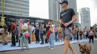 Warga berolahraga saat sejumlah orang yang mengenakan batik berjalan di catwalk sepanjang Jalan Jenderal Sudirman, Jakarta, Minggu (2/10/2022). Kegiatan yang diikuti ratusan orang ini diselenggarakan oleh Bank Mandiri untuk menyambut Hari Batik Nasional yang jatuh setiap tanggal 2 Oktober 2022. (Liputan6.com/Faizal Fanani)