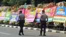 Petugas kepolisian berdiri di dekat karangan bunga ucapan selamat yang berjejer di sekitar Gedung Merah Putih KPK, Jakarta, Jumat (20/12/2019). Papan karangan bunga tersebut berisi ucapan selamat terhadap dilantiknya pimpinan KPK periode 2019-2023. (merdeka.com/Imam Buhori)