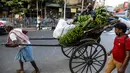 Seorang pria duduk di atas becak yang ditarik dengan tangan membawa pisang dan bahan-bahan lain untuk ibadah menjelang festival Hindu Chhat, di Kolkata, India (9/11/2021). (AP Photo/Bikas Das)