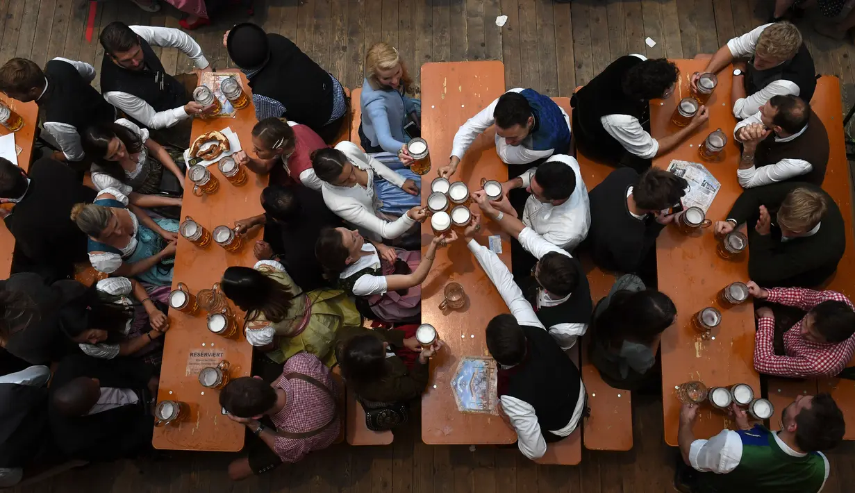 Pengunjung menikmati bir selama Festival Oktoberfest 2019 di sebuah tenda di Munich, Jerman selatan (3/10/2019). Festival bir terbesar di dunia Oktoberfest berlangsung hingga 6 Oktober 2019. (AFP Photo/Christof Stache)