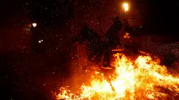 Seorang pria menunggangi kuda melewati api unggun saat festival Luminarias di San Bartolome de Pinares, Spanyol, Jumat (16/1/2020). Tradisi yang sudah berlangsung lebih dari 500 tahun ini bertujuan untuk menyucikan binatang yang identik dengan Santo Antonius. (AP Photo/Manu Fernandez)