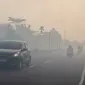Para pengendara bermotor menyalakan lampu depan kendaraan saat melintasi jalan yang diselimuti kabut asap di Kota Palangka Raya, Kalimantan Tengah, Kamis,  20 Agustus 2026. (AFP/ Reina)