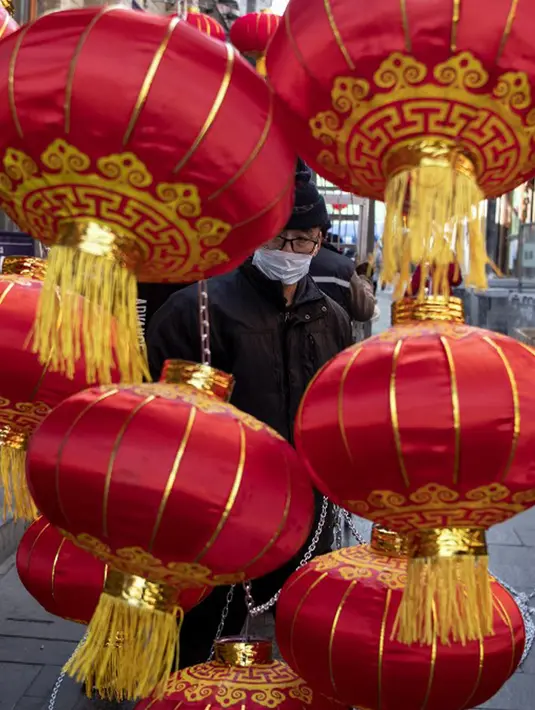 Seorang pekerja memasang lentera tradisional Tiongkok di sepanjang gang menjelang Tahun Baru Imlek di Beijing, China, 2 Februari 2021. Imlek tahun ini jatuh pada tanggal 12 Februari 2021. (NOEL CELIS/AFP)