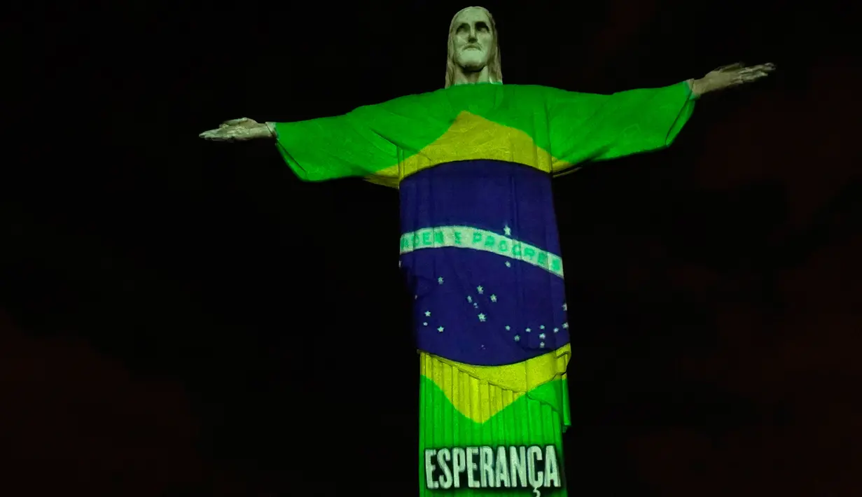 Patung Christ the Redeemer atau Yesus sang Penebus yang populer di dunia menyala dengan gambar bendera Brasil bertuliskan 'harapan' pada hari Paskah di Rio de Janeiro, Brasil, Minggu (12/4/2020). Pertunjukkan itu bentuk dukungan dan semangat untuk melawan pandemi COVID-19. (AP/Silvia Izquierdo)