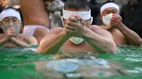 Seorang penganut Shinto dari Kuil Teppozu Inari mandi dengan air dingin untuk mensucikan jiwa dan tubuh mereka selama ritual Tahun Baru di Tokyo, Jepang, Minggu (9/1/2022). Ritual tahunan mandi air dingin ini bertujuan mengharapkan kesehatan serta keberuntungan di tahun yang baru. (Philip FONG/AFP)