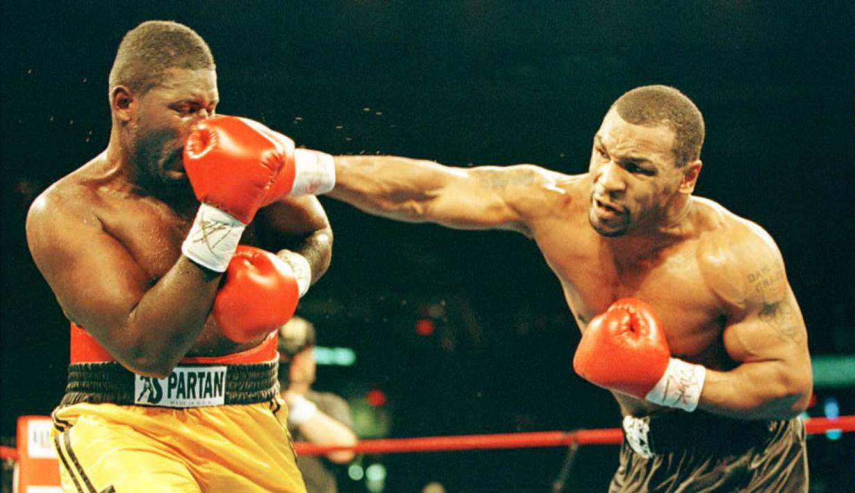 Mike Tyson adalah petinju paling kontroversial dan juga legenda yang memiliki pukulan keras. Dari 50 Kemenangan, 44 diantaranya menang KO. Foto ini saat Mike Tyson (kanan) melawan Buster Mathis Jr. di Spectrum, Philadelphia. (AFP/Timothy A. Clary) 