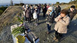 Sejumlah orang berdoa ke arah laut untuk mengenang para korban bencana gempa dahsyat dan tsunami besar di Jepang pada 11 Maret 2011 silam, di Minamisoma, Prefektur Fukushima, Jumat (11/3/2016). (REUTERS/Kyodo)