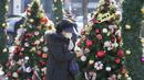 Seorang perempuan yang mengenakan masker berjalan di dekat dekorasi Natal di Incheon, Korea Selatan, Rabu (8/12/2021). Jumlah kasus harian COVID-19 baru di Korea Selatan melebihi 7.000 kasus untuk pertama kalinya sejak pandemi corona merebak. (AP Photo/Lee Jin-man)