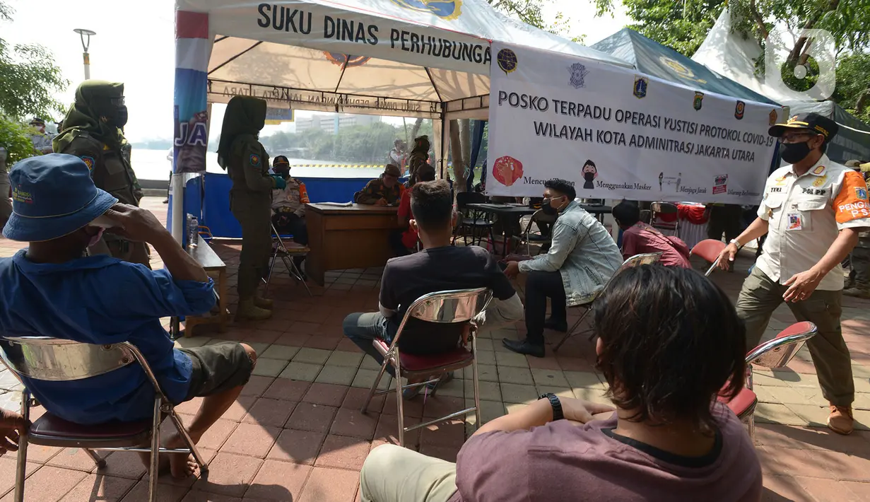 Pelanggar mengikuti sidang di tempat saat Operasi Yustisi di Kawasan Danau Sunter, Jakarta, Rabu (16/9/2020). Warga yang melanggar protokol Covid-19 langsung disidang tindak pidana ringan (tipiring) di tempat dengan membayar denda Rp 55.000 maupun sanksi sosial. (merdeka.com/Imam Buhori)