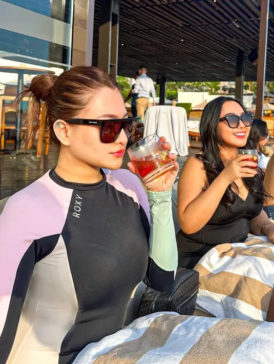 Menikmati sunset di pantai, Nathalie tampil sporty dengan swimsuit hitam. [Instagram/nathalieholscher]