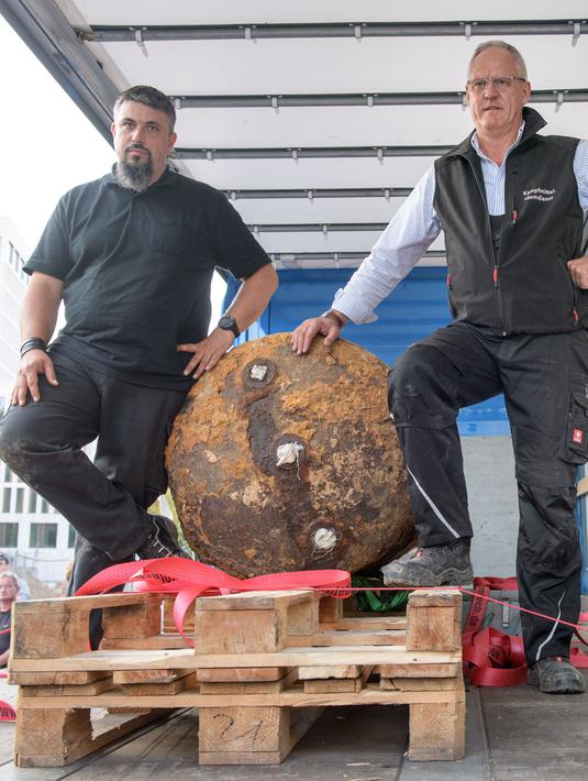 Pakar bom Rene Bennert dan Dieter Schweizler berpose di dekat bom Perang Dunia II di Frankfurt, Jerman, (3/9). Bom tersebut ditemukan di sebuah lokasi konstruksi yang dekat dengan kompleks Goethe University Frankfurt. (AFP Photo/Thomas Lohnes)