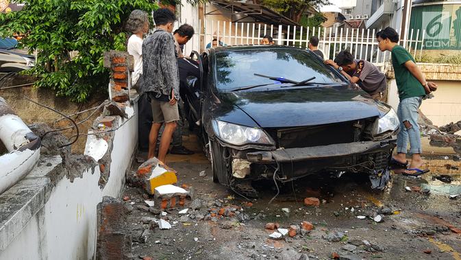 Warga melihat kondisi mobil yang mengalami kecelakaan tunggal di kawasan Pasar Minggu, Jakarta Selatan, Sabtu (8/6/2019). Mobil yang nyaris tercebur sungai itu dikendarai seorang pemuda yang nekat melakukan aksi kebut-kebutan saat jalanan ibu kota lengang. (Liputan6.com/Herman Zakharia)