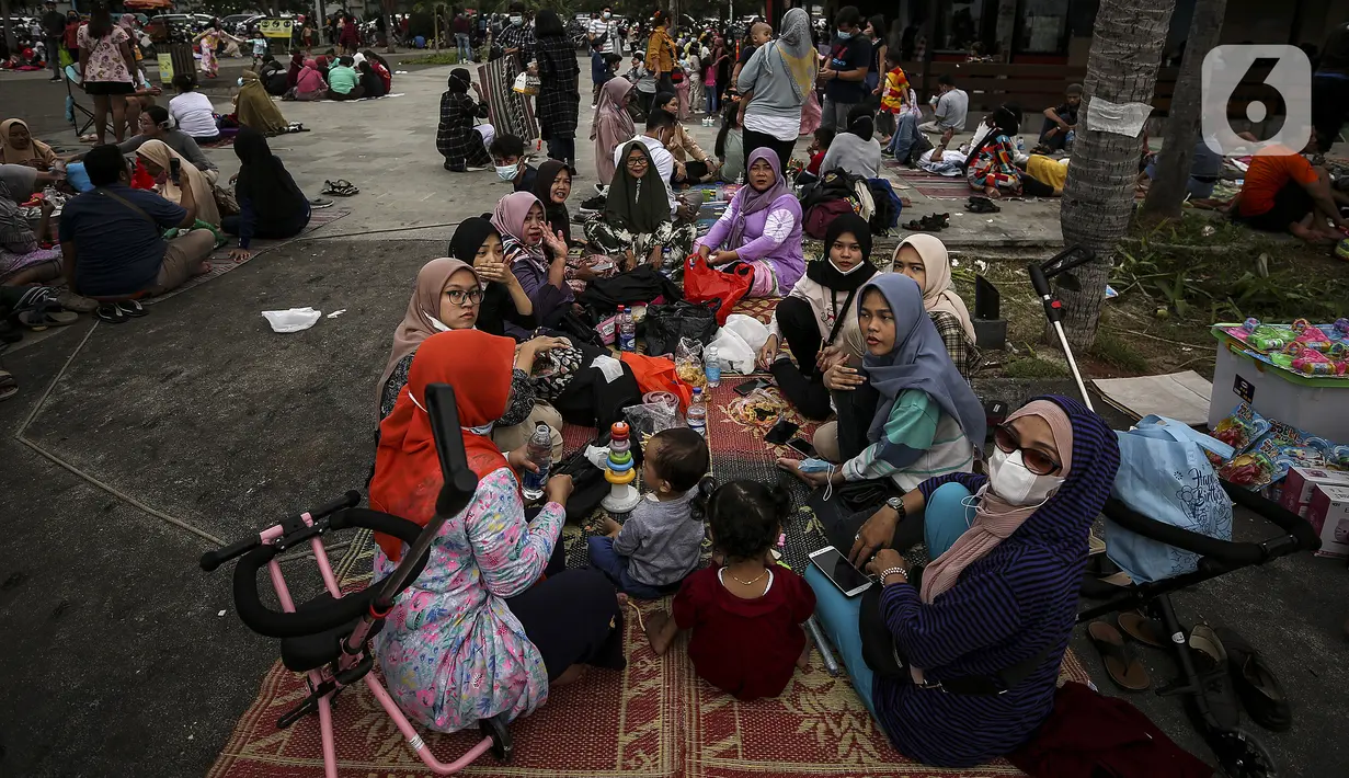 Pengunjung beristirahat saat berwisata di Pantai Karnaval Ancol, Jakarta, Jumat (14/5/2021). Pemprov DKI Jakarta pada libur Lebaran 2021 membuka sejumlah tempat wisata, salah satunya Ancol. (Liputan6.com/Johan Tallo)