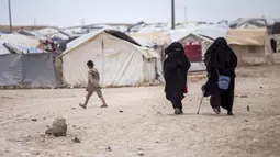 Dua wanita berjalan di Kamp al-Hol, Provinsi Hasakeh, Suriah, Sabtu (1/5/2021). Pejabat Kurdi mengatakan keamanan telah meningkat di kamp yang luas di timur laut Suriah, tetapi kekhawatiran berkembang dari wabah virus corona COVID-19 di fasilitas itu. (AP Photo/Baderkhan Ahmad)