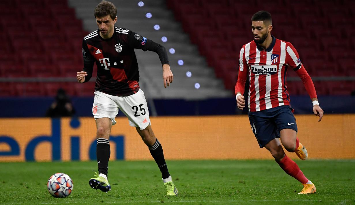 Gelandang Atletico Madrid, Yannick Ferreira-Carrasco dan penyerang Bayern Munchen, Thomas Mueller berebut bola pada matchday kelima Grup A Liga Champions di Stadion Wanda Metropolitano, Madrid, Rabu (2/12/2020) dini hari WIB. Atletico Madrid vs Bayern Munchen imbang 1-1. (PIERRE-PHILIPPE MARCOU/AFP)