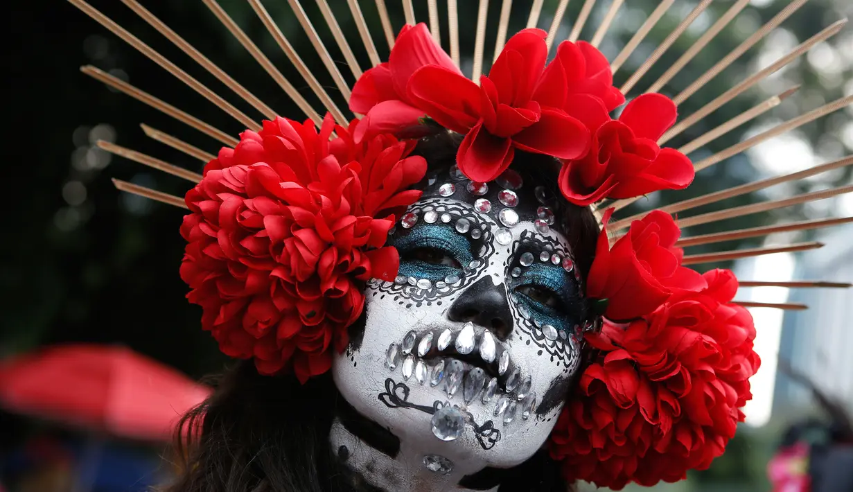 Seorang wanita berdandan ala tengkorak saat mengikuti parade Hari Orang Mati di Mexico City, Meksiko, Sabtu (26/10/2019. Para peserta dalam parade ini mengenakan kostum dan melukis wajah mirip dengan tokoh tengkorak Meksiko yang ikonik, Catrina. (AP Photo/Ginnette Riquelme)