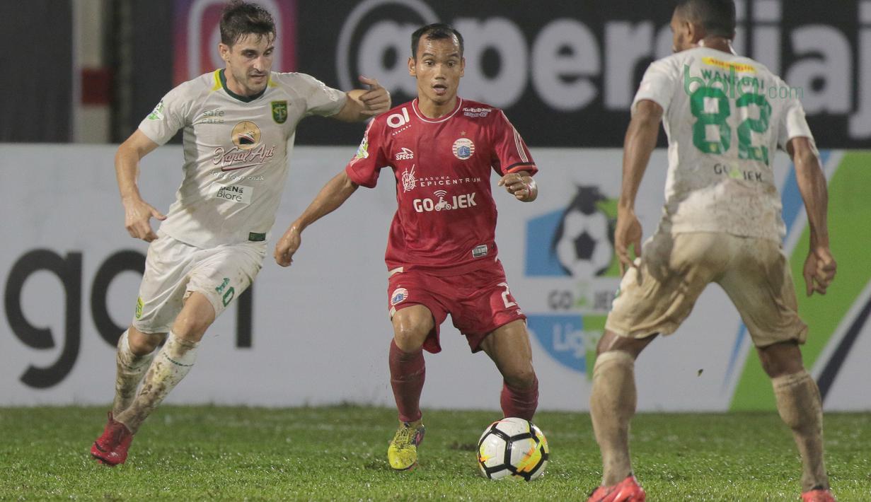 Pemain Persija Jakarta, Riko Simanjuntak (tengah) mencoba melewati adangan pemain Persebaya pada laga Gojek Liag 1 bersama Bukalapak di Stadion PTIK, Jakarta (26/6/2018). Persija dan Persebaya bermain imbang 1-1. (Bola.com/Nick Hanoatubun)